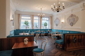 Ein Restaurant mit einer Sitzgruppe in grünen Boxsitzgelegenheiten, Holztischen und einem Kronleuchter.
