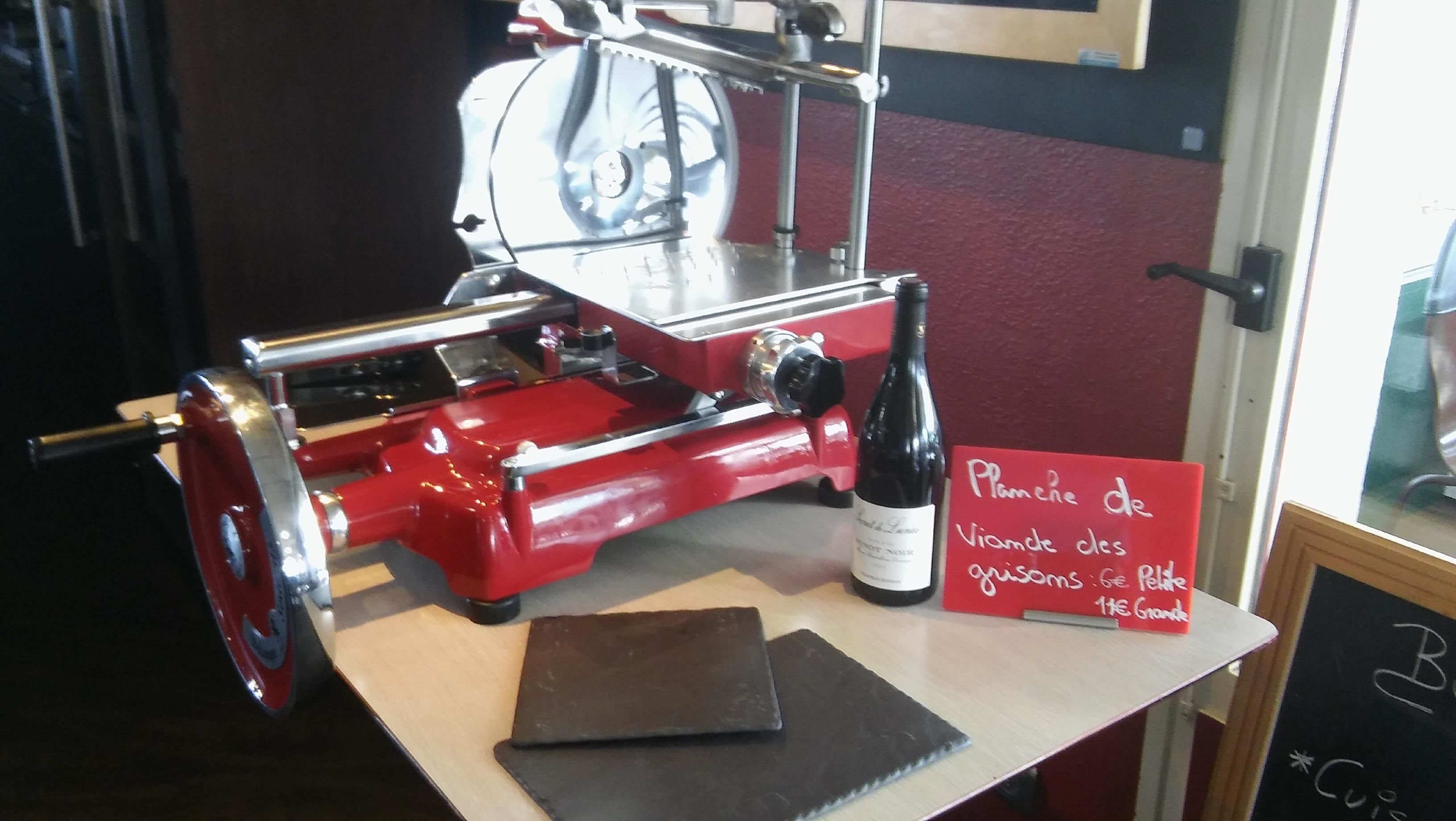 Eine rote Fleischmaschine auf einem Tisch mit einer Weinflasche und einem Schild auf Französisch.