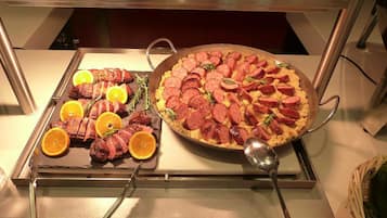 Un buffet proposant des viandes en tranches et une grande pizza.