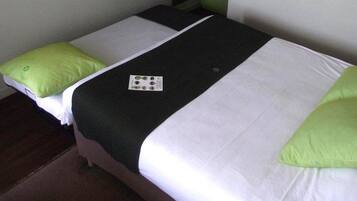 A hotel room with two beds, each with white and green bedding, and a black blanket.
