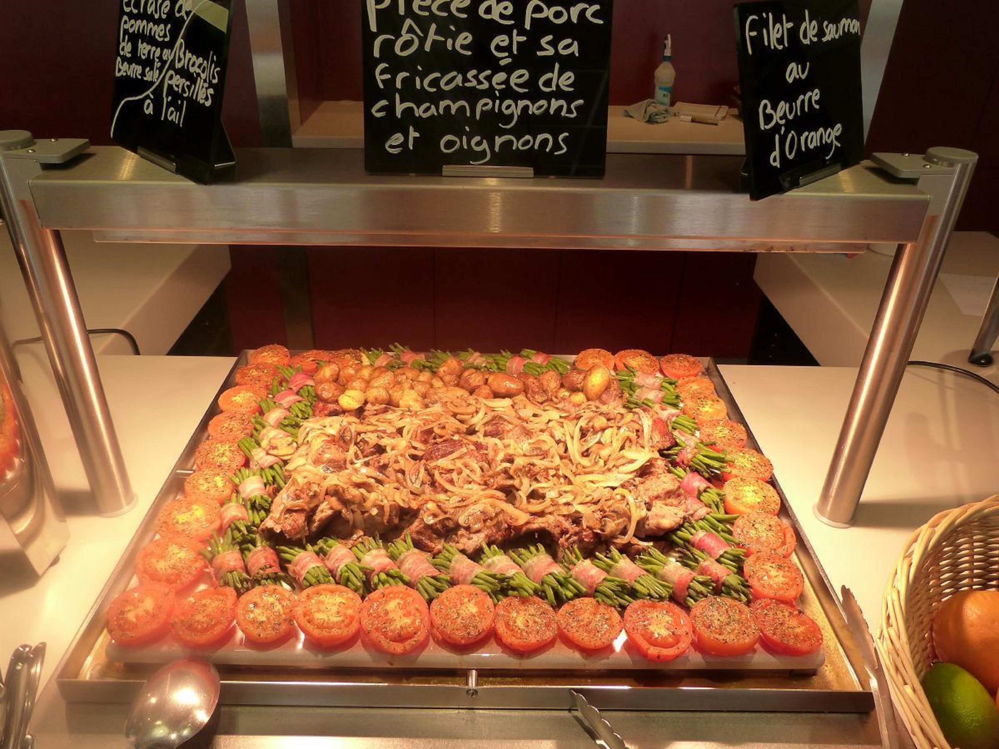 Un bufé con una variedad de platos, incluyendo patatas asadas, cerdo y una ensalada.
