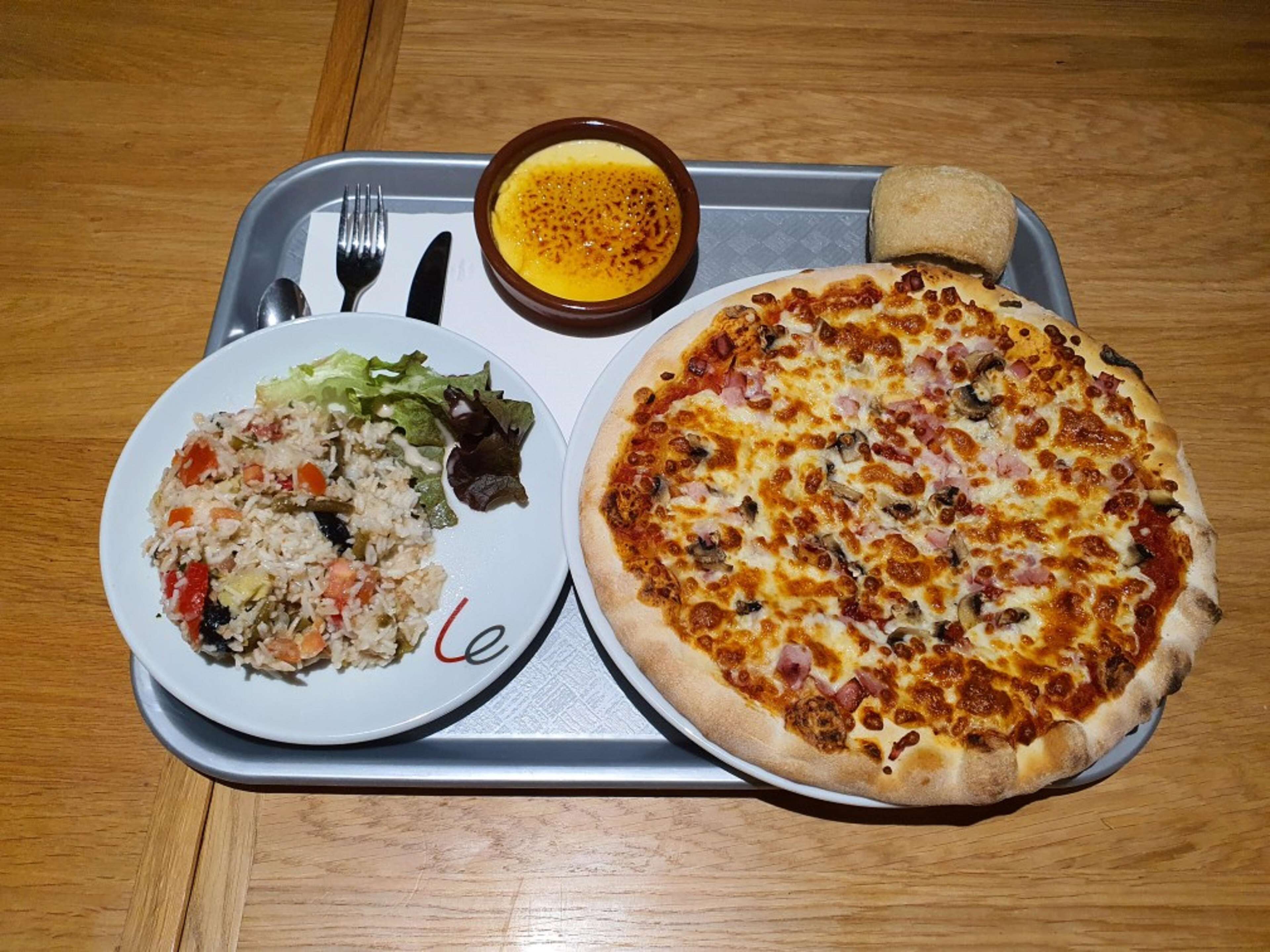 A tray with a pizza, a salad, and a bowl of soup.
