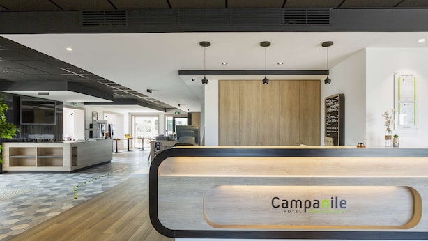 Mostrador de recepción de hotel con detalles de madera y un letrero que dice 'Campanile Hotel'.
