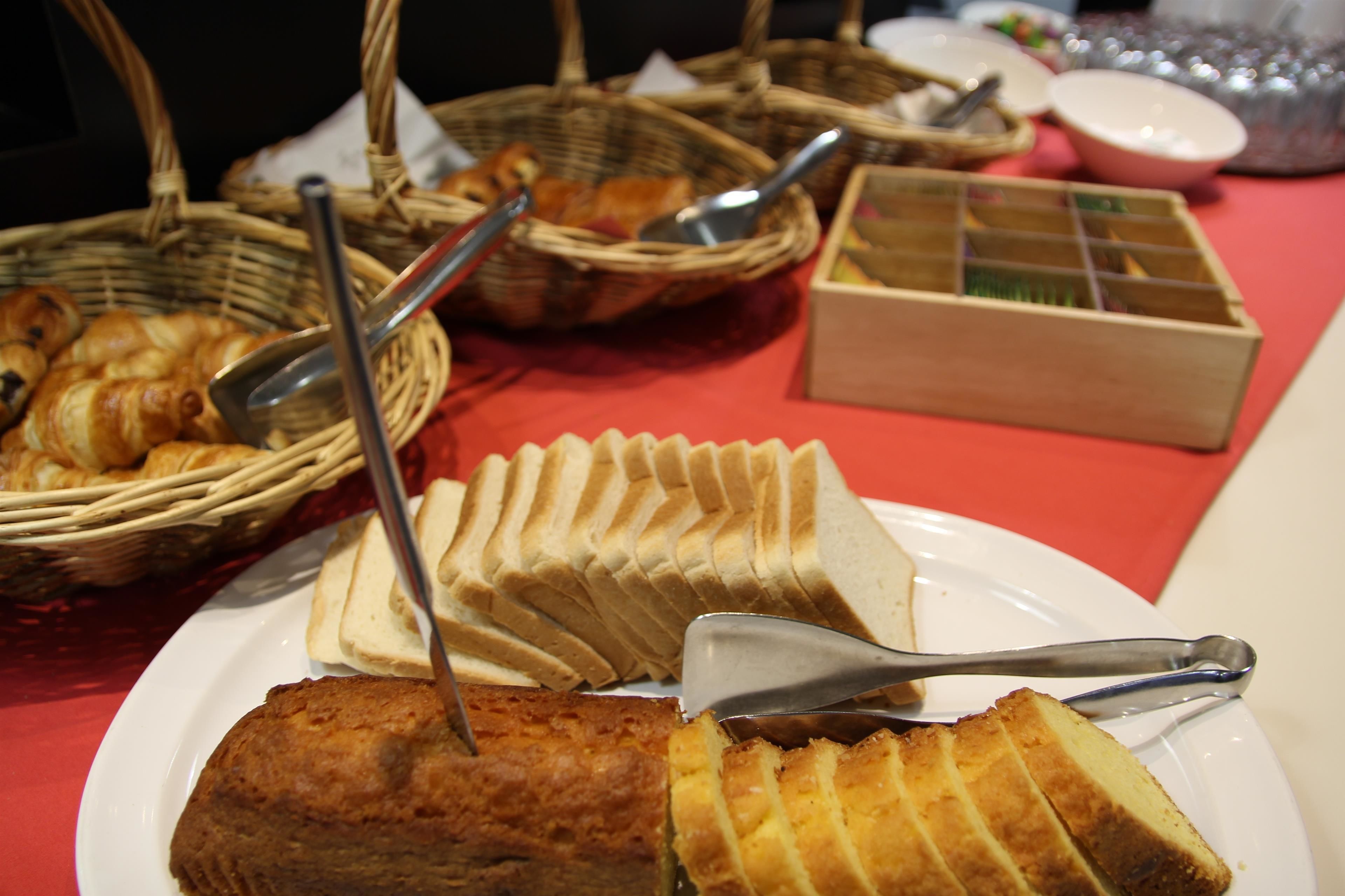 Una mesa con diferentes alimentos, como pan, pasteles y una caja de bombones.
