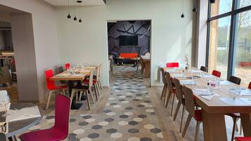 A modern dining area with hexagonal patterned flooring, wooden tables, and red chairs.