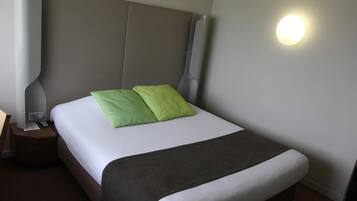 A neatly made bed with a white and gray bedspread, two green pillows, and a brown blanket.