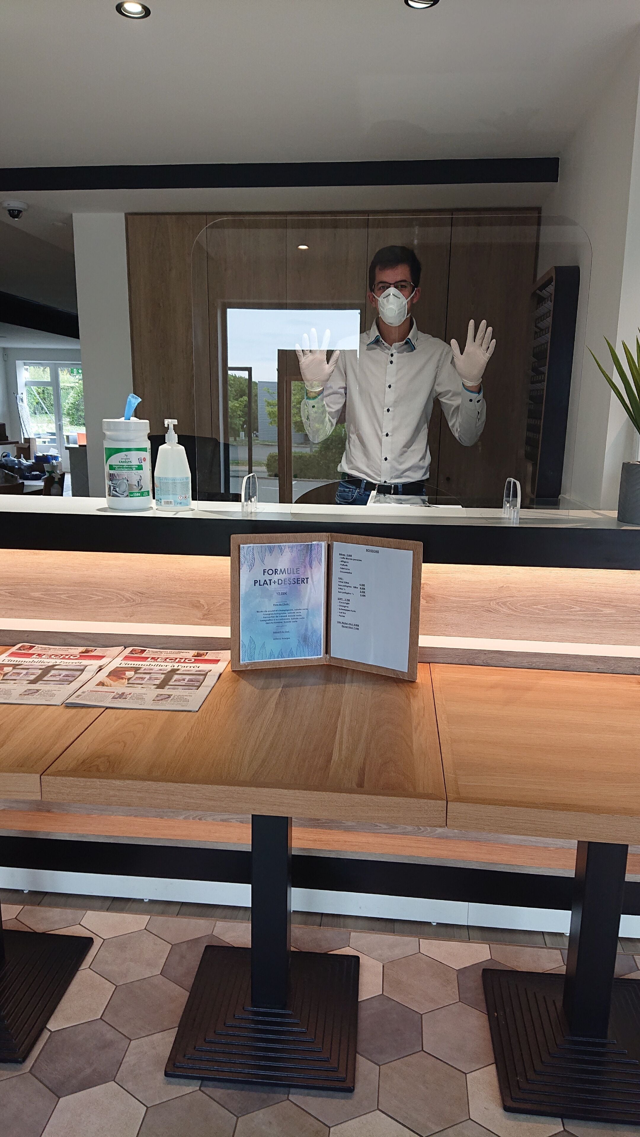 A reception area with a wooden counter, a menu board, and a window view.