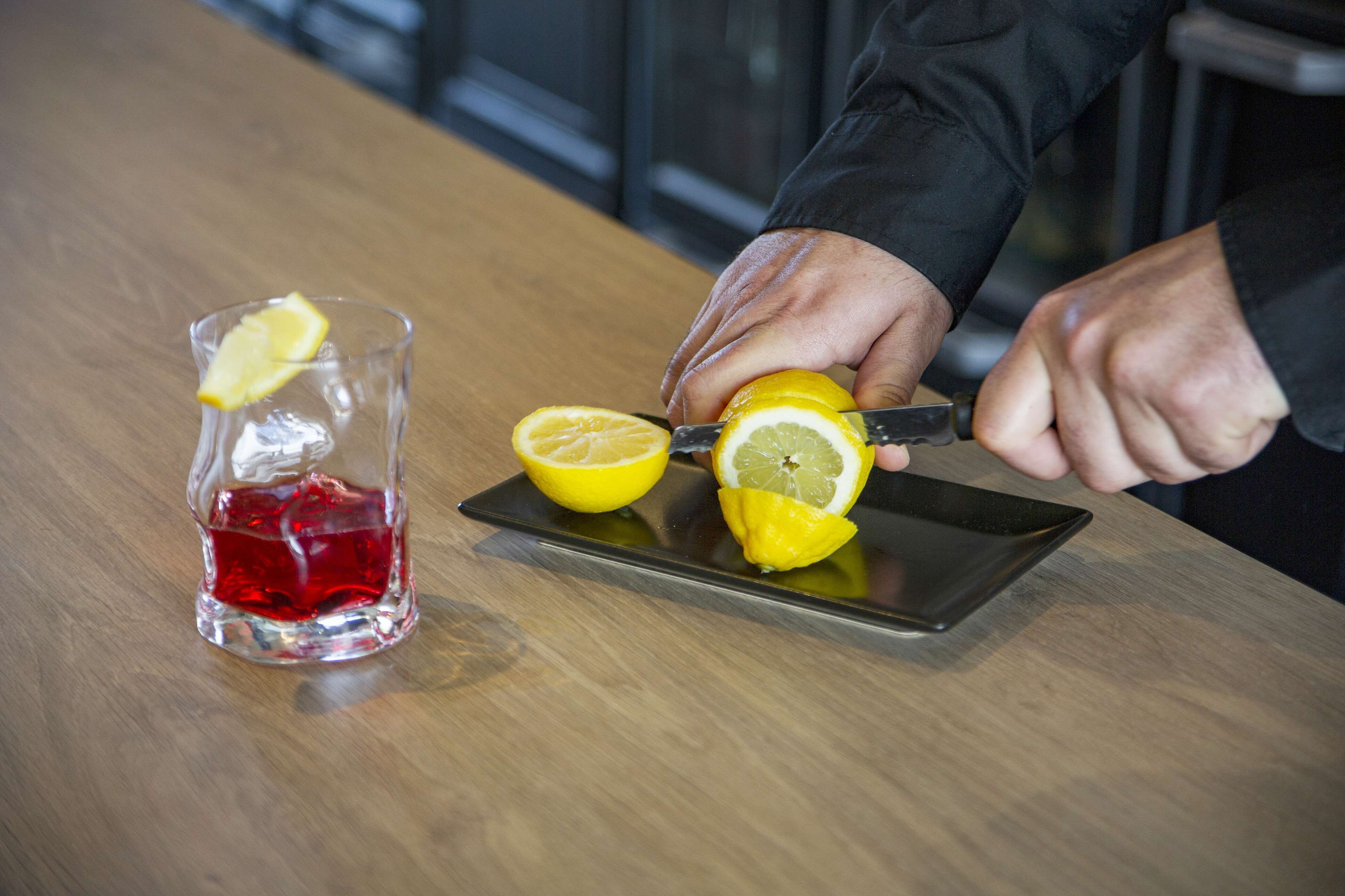 A person slicing a lemon on a wooden table.