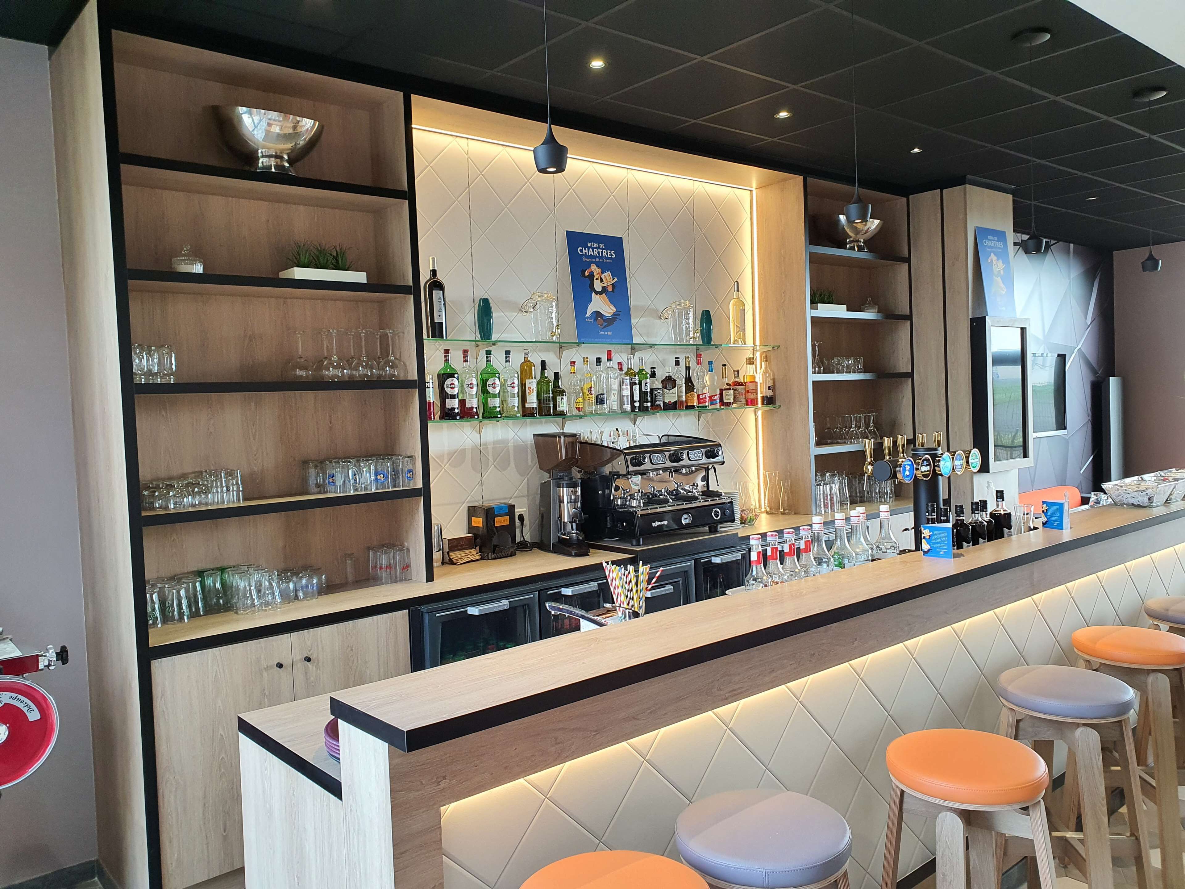 A bar area with shelves of bottles, glasses, and a coffee machine.