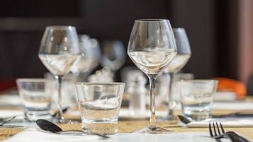 A dining table set with multiple wine glasses and water glasses, utensils, and a napkin.