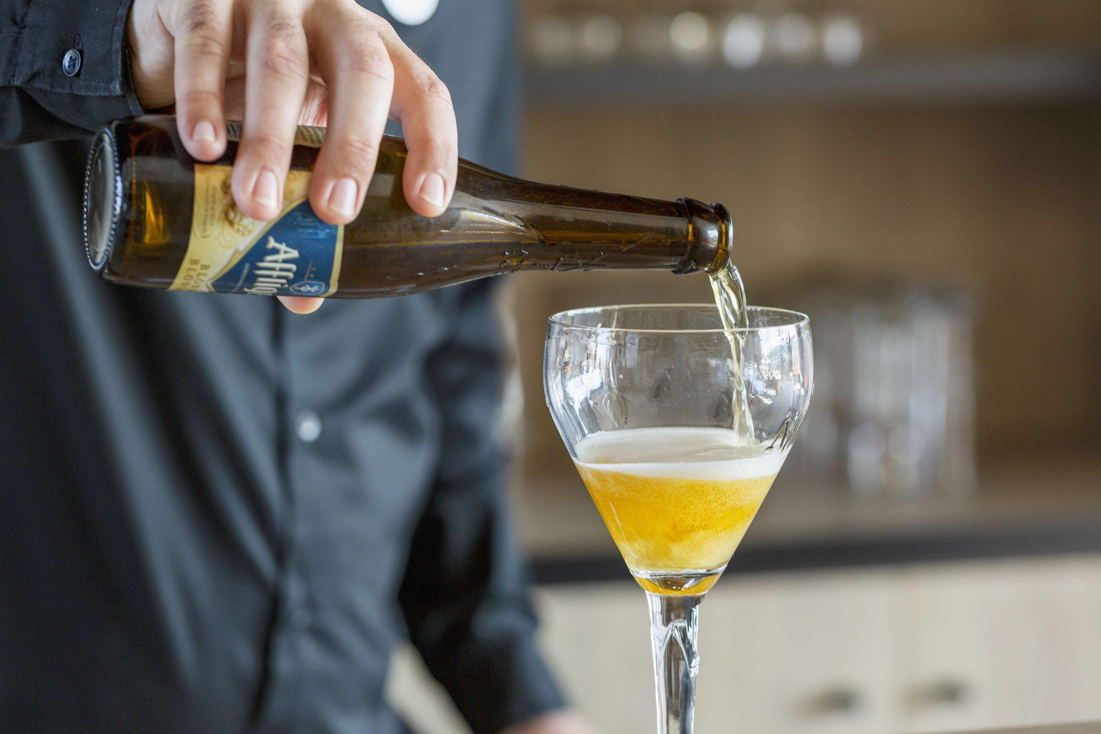 Una persona sirviendo cerveza en un vaso.