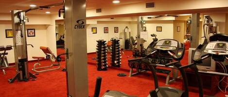 A gym with various exercise equipment, including treadmills, weight machines, and free weights.