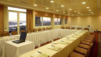 A conference room with a long table, chairs, and a laptop on a table.