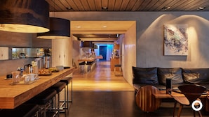 Una cocina moderna con una barra de madera, taburetes y un comedor con mesa y sillas.