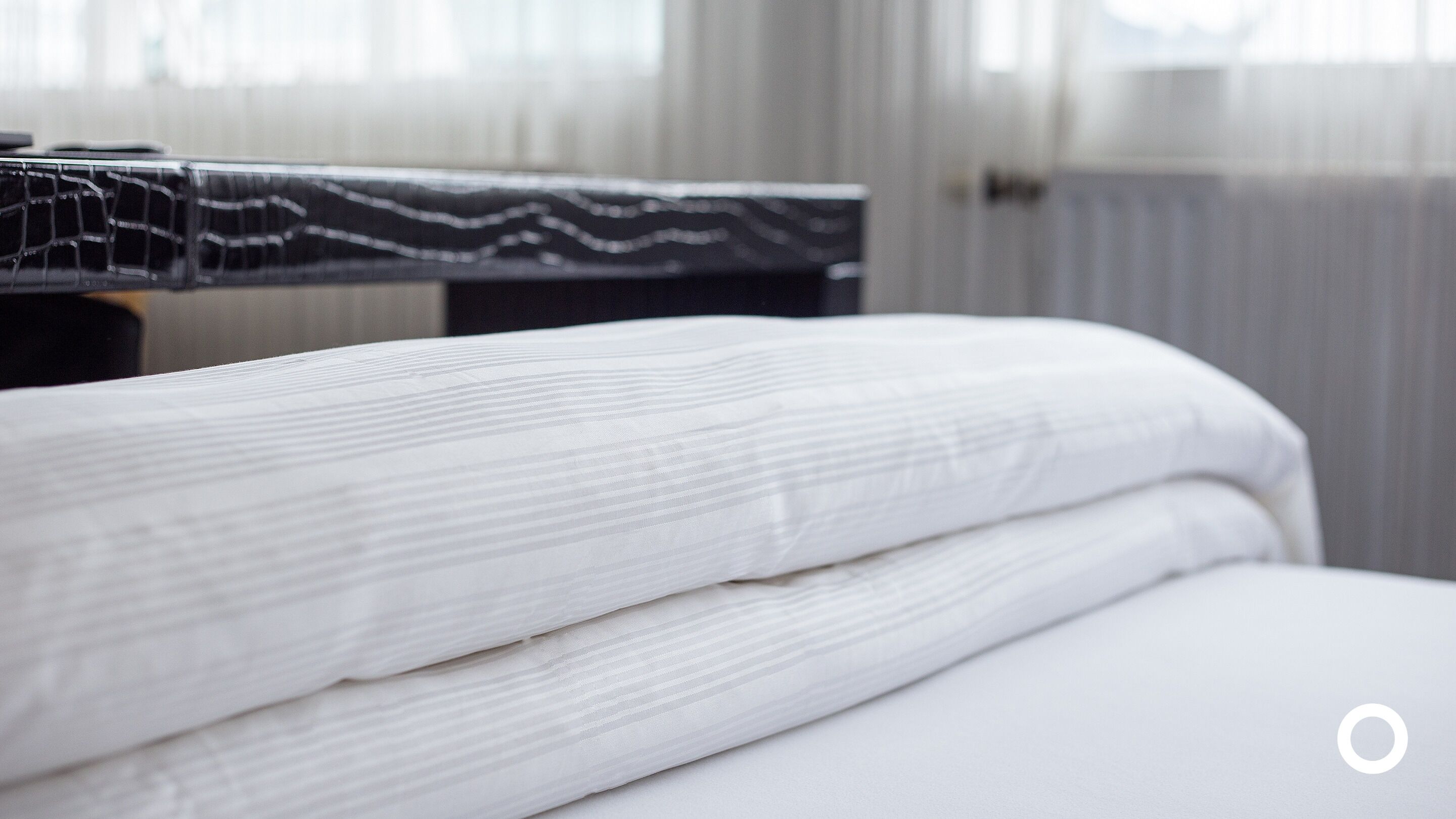 Cama bem arrumada com lençóis brancos em um quarto de hotel.