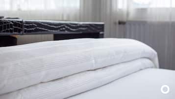 Cama bem arrumada com lençóis brancos em um quarto de hotel.