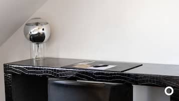 A modern, sleek desk with a black marble top, a clear glass vase with a black object inside, and a small white card on the surface.