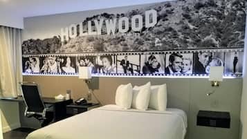 Habitación de hotel con un enorme mural con temática de Hollywood, una cama, un escritorio y una silla.