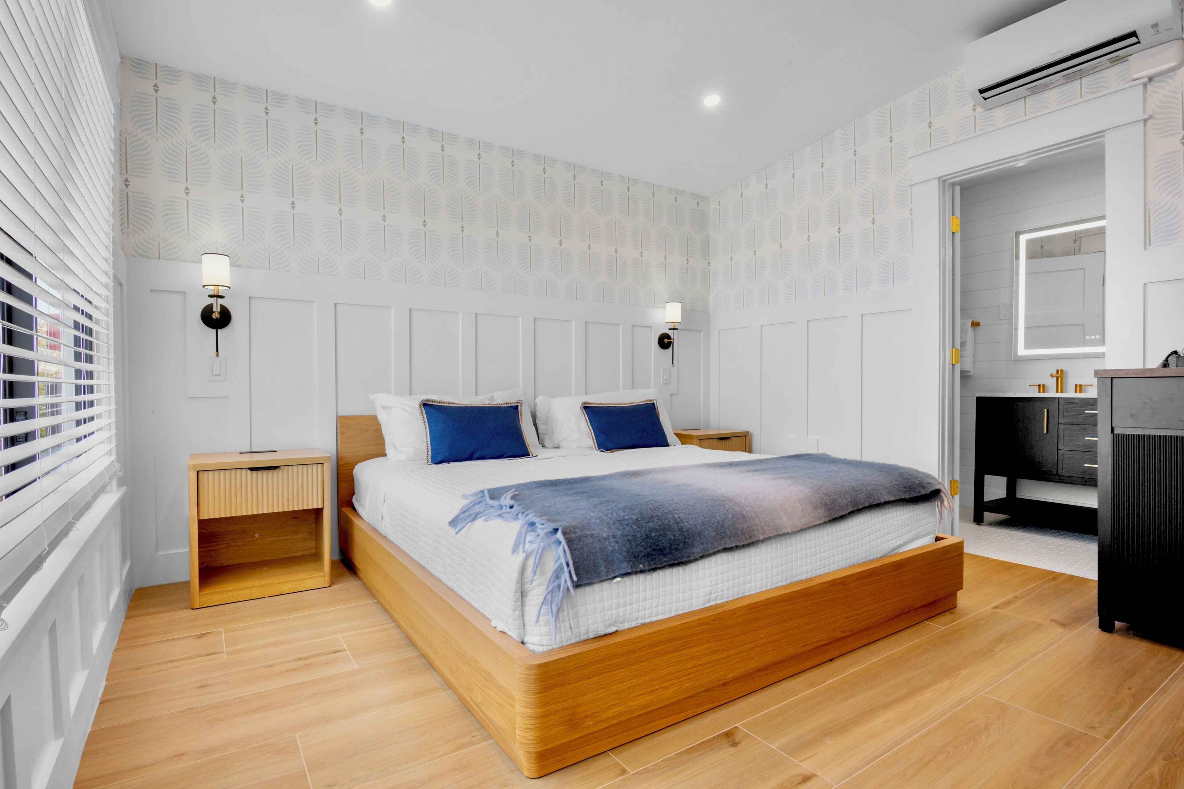 A bedroom with a wooden bed, white walls, and a patterned wallpaper.