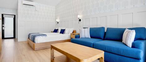 Ein modernes Zimmer mit einem Bett, einem blauen Sofa, einem Holztisch und strukturierter Tapete.