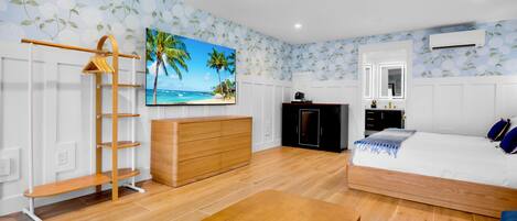 A bedroom with a wooden bed, a dresser, a desk, a wardrobe, and a painting of a beach scene.