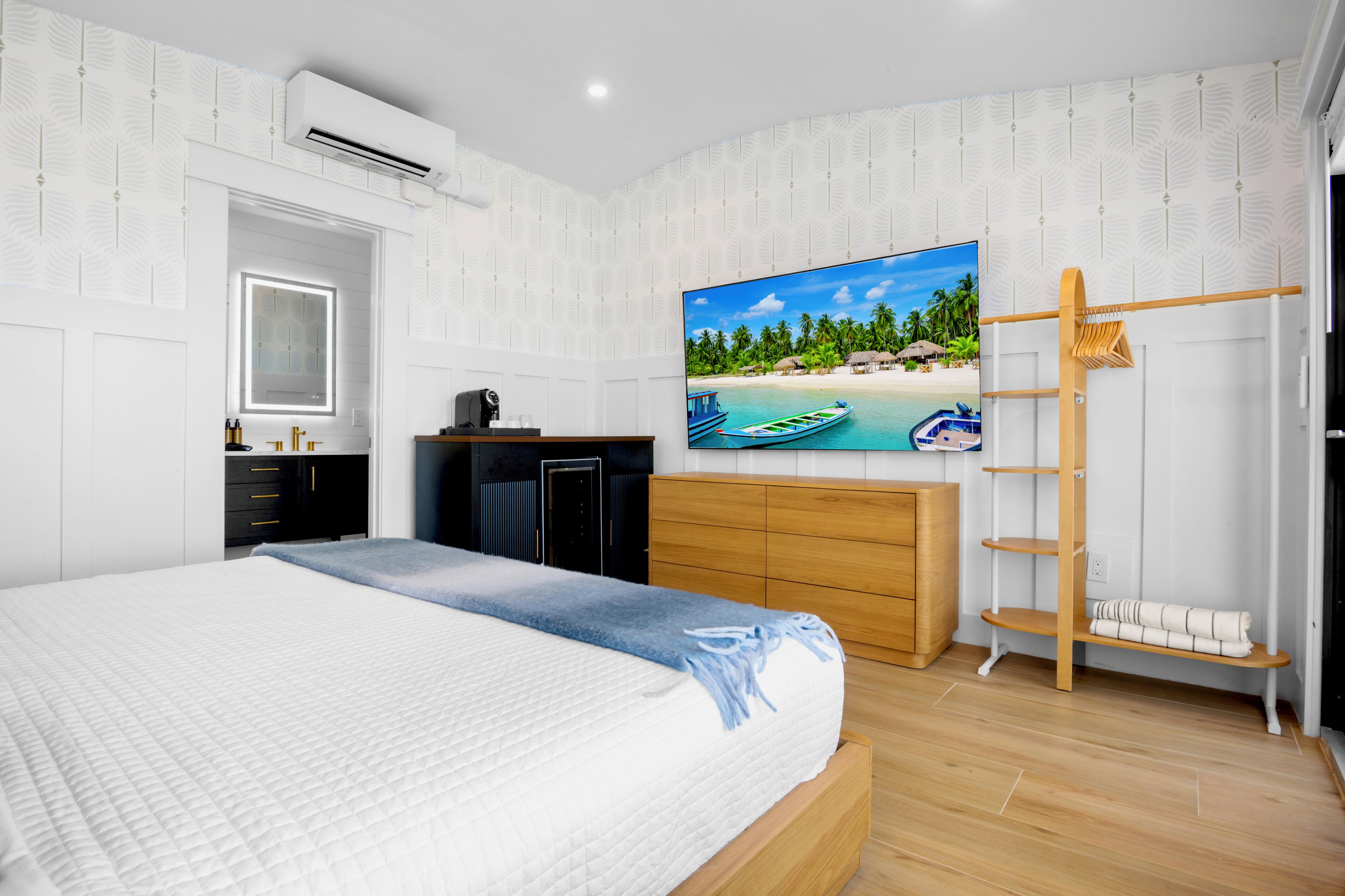 A bedroom with a bed, a TV, a wardrobe, a desk, and a shelf.