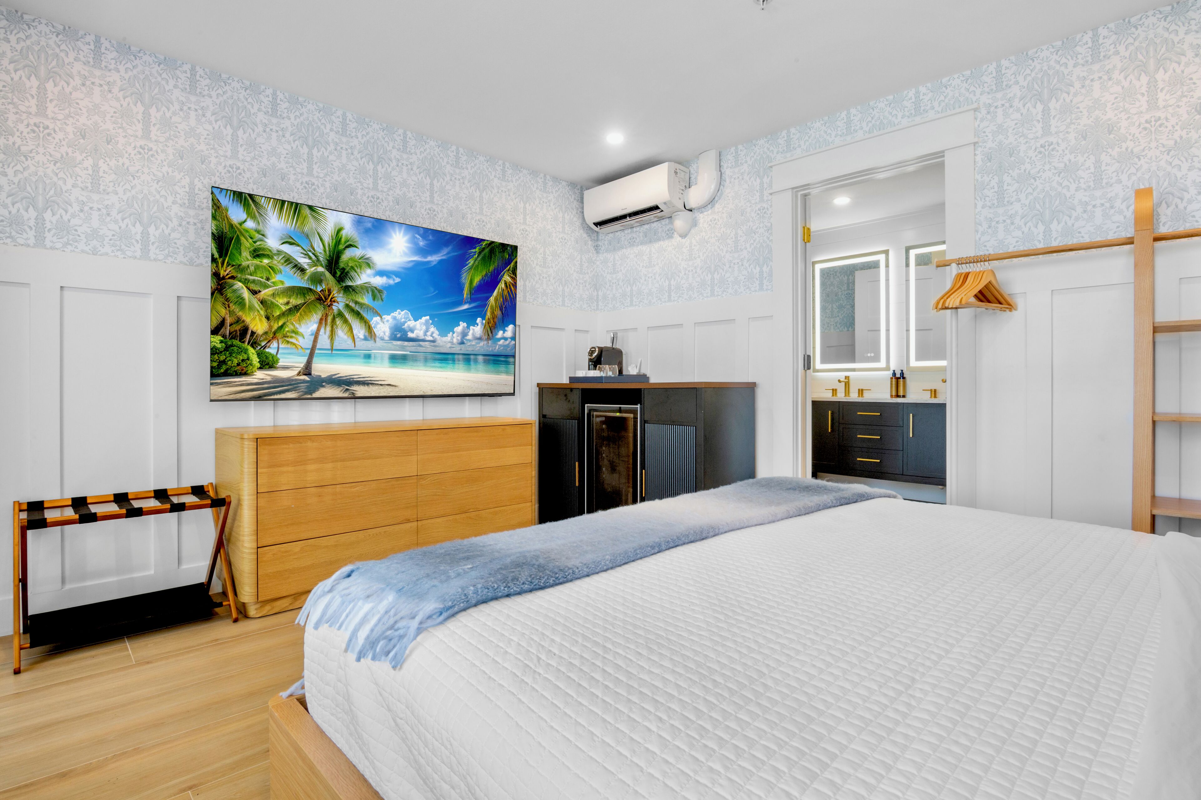 Une chambre à coucher comprenant un lit, une télévision, une armoire, un miroir et un appareil de climatisation.