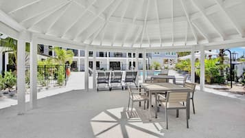A covered outdoor area with a pool, lounge chairs, and a dining table.