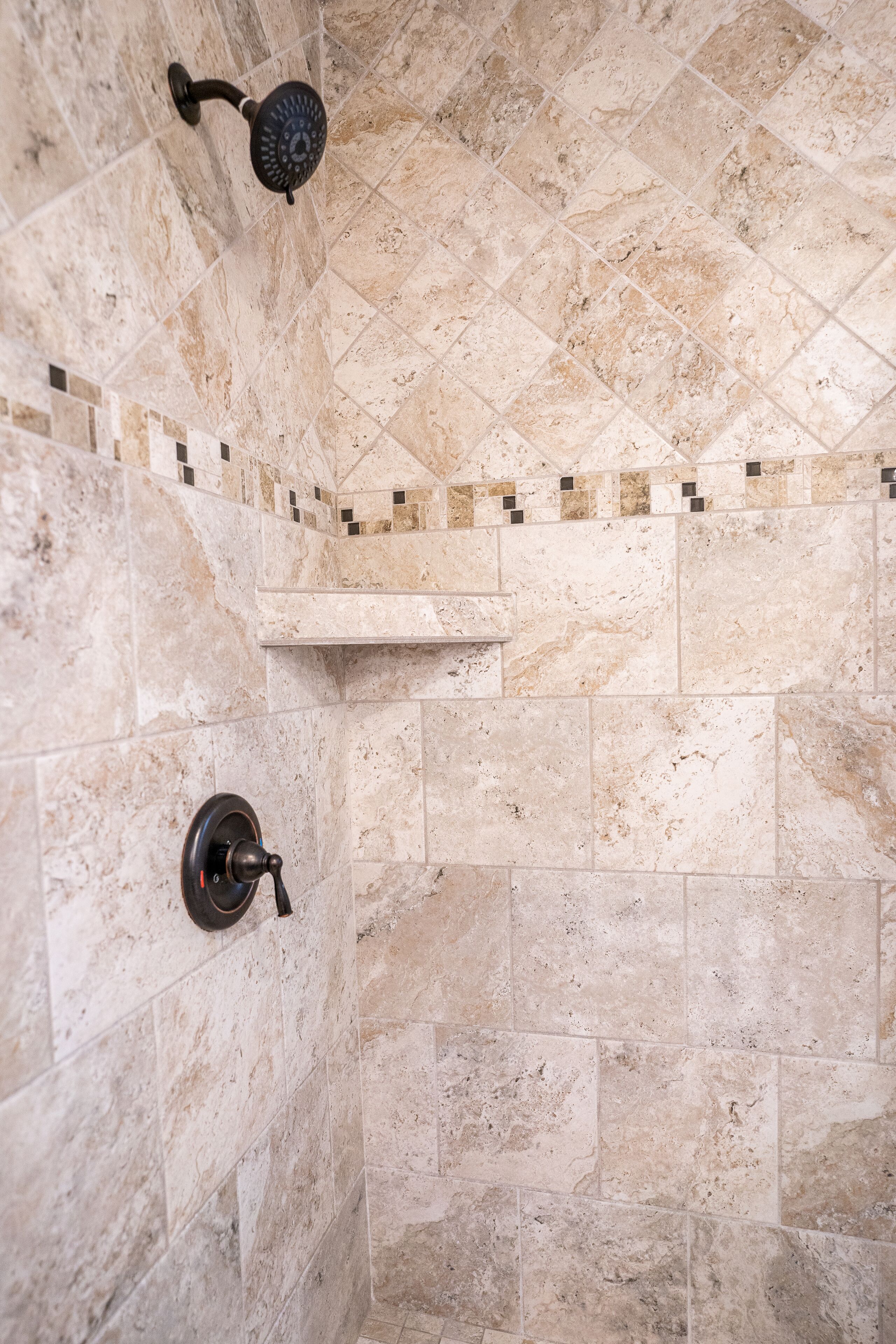 A shower area with a handheld showerhead and a wall-mounted control valve.