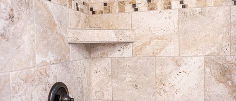 A shower area with a handheld showerhead and a wall-mounted control valve.