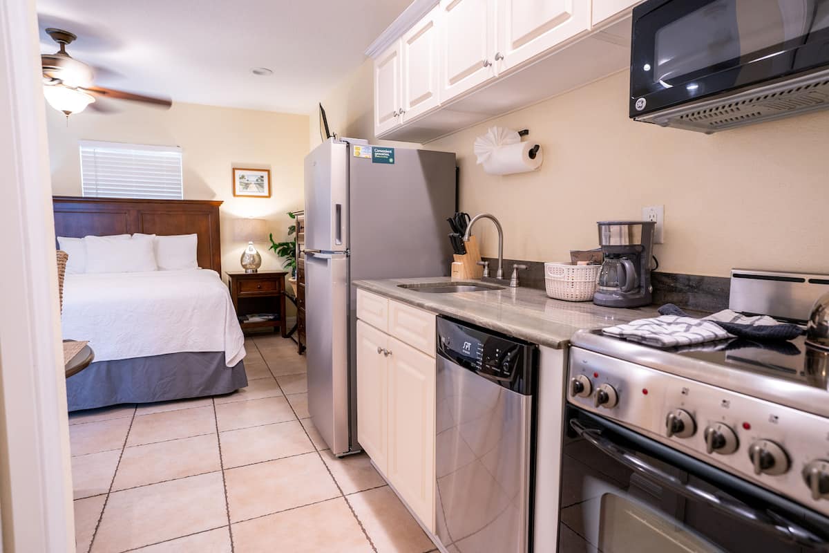 A compact kitchen with a refrigerator, dishwasher, stove, microwave, and a sink.