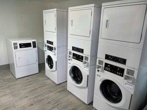 A row of stacked laundry machines in a room with wooden flooring.