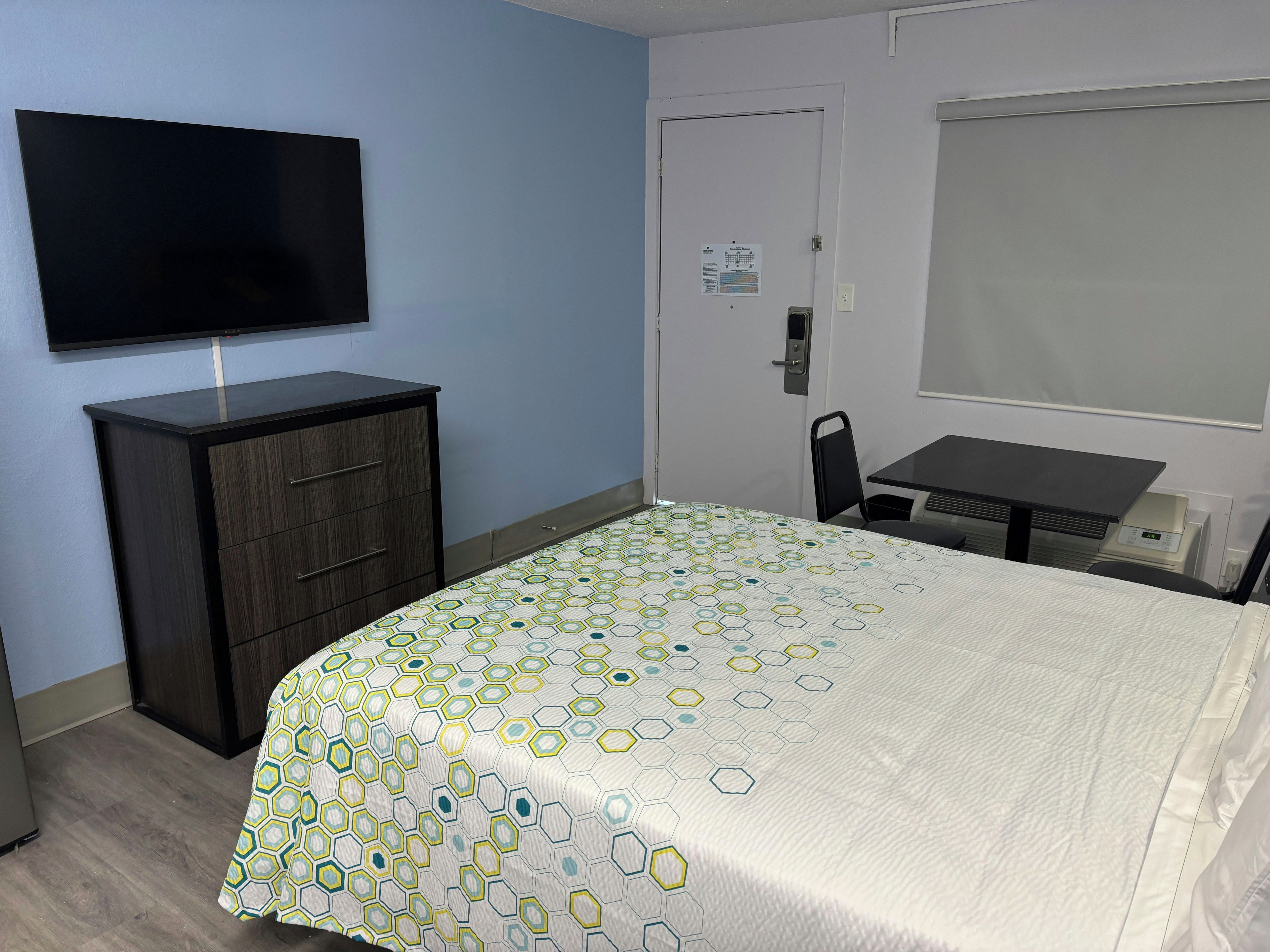 Una habitación de hotel con una cama, un escritorio, una silla, un televisor y un armario.