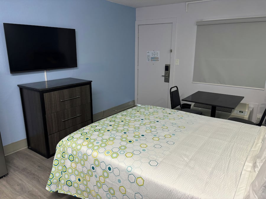 A hotel room with a bed, a desk, a chair, a television, and a wardrobe.