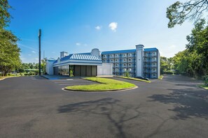 A modern hotel with a central building and a parking lot. - HomeTowne Studios by Red Roof Birmingham - Airport (Birmingham)