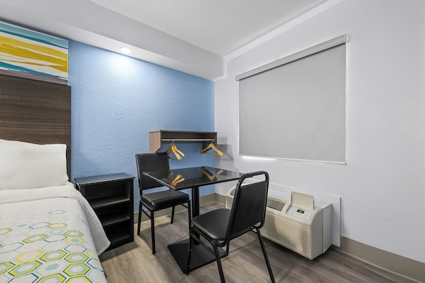 Habitació d'hotel amb un llit, una taula de treball amb cadira, un calefactor i una finestra.