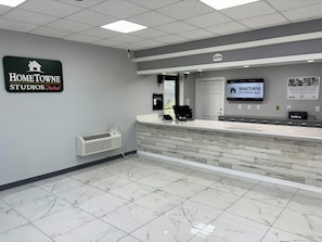 Un área de recepción con mostrador, un letrero de HomeTowne Studios y un televisor montado.