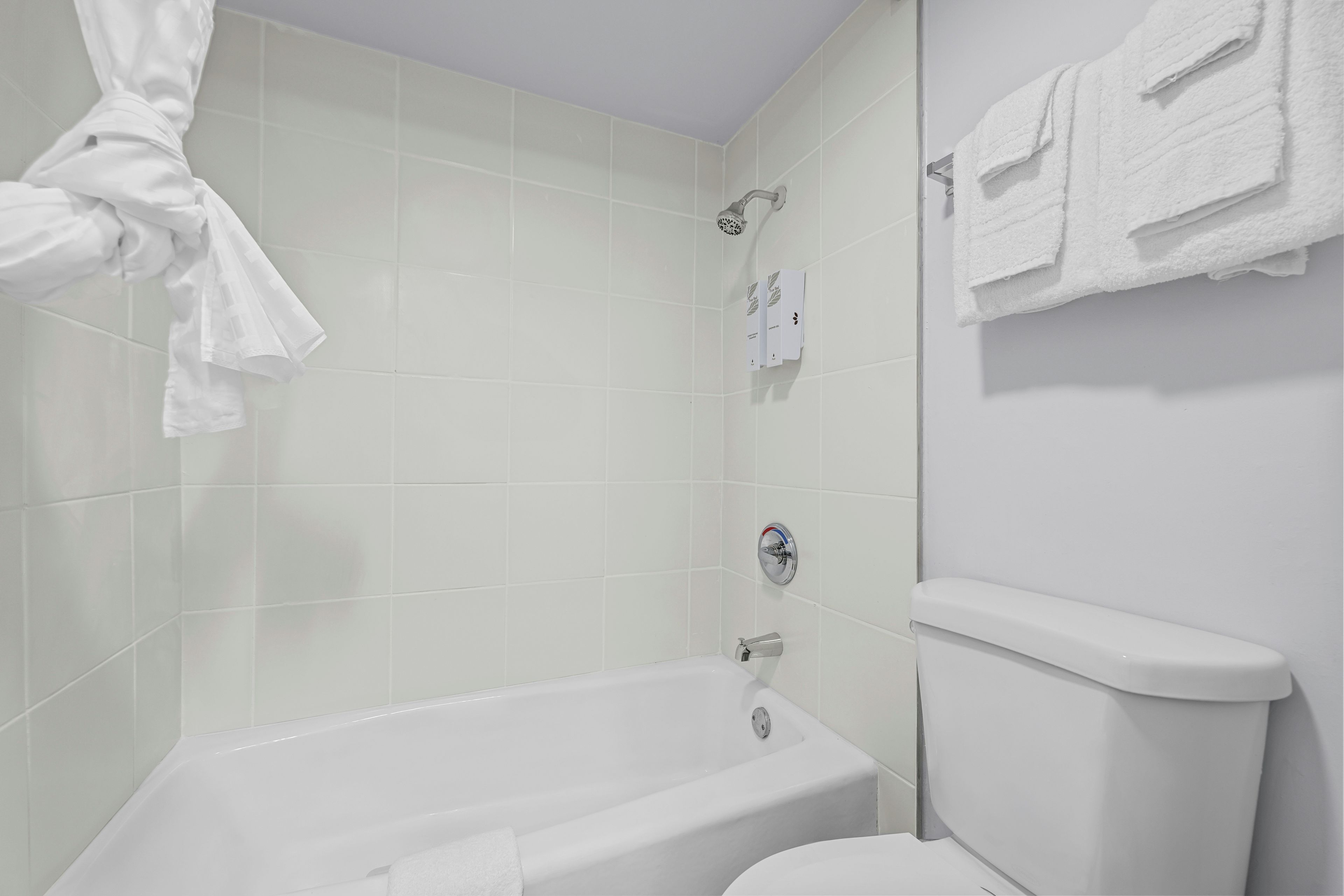 A bathroom with a bathtub, toilet, and towel rack.