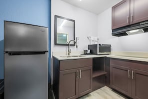 A compact kitchen with a refrigerator, sink, and microwave.