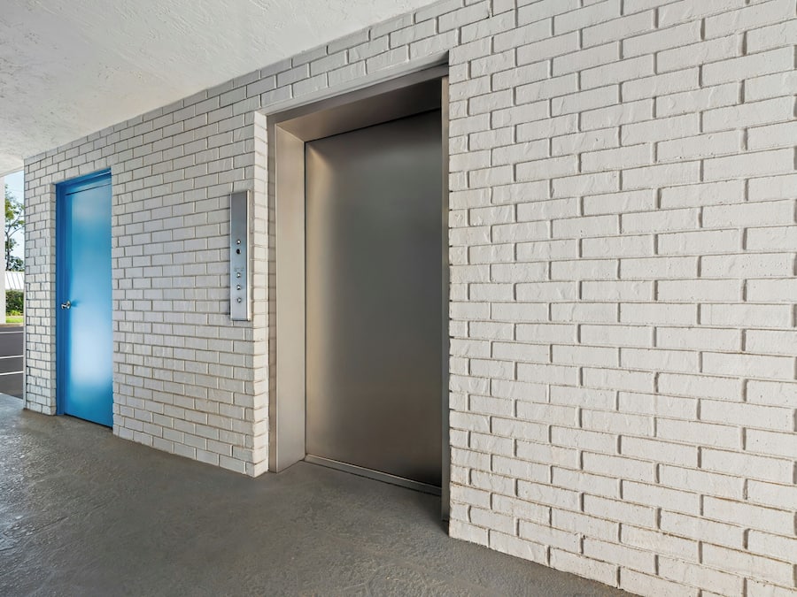 A modern building entrance with a blue door and an elevator.