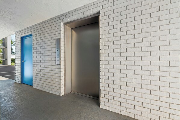 A modern building entrance with a blue door and an elevator.