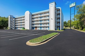 A multi-story hotel with a parking lot in front.