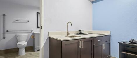 A bathroom with a toilet, sink, and cabinets.