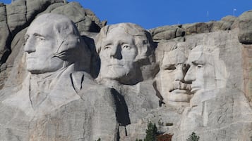 Une grande formation rocheuse ornée de sculptures représentant des visages.