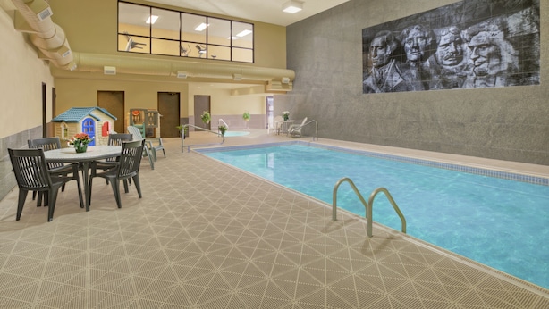 Una piscina interior con suelo de baldosas, un mural en la pared y una mesa con sillas.