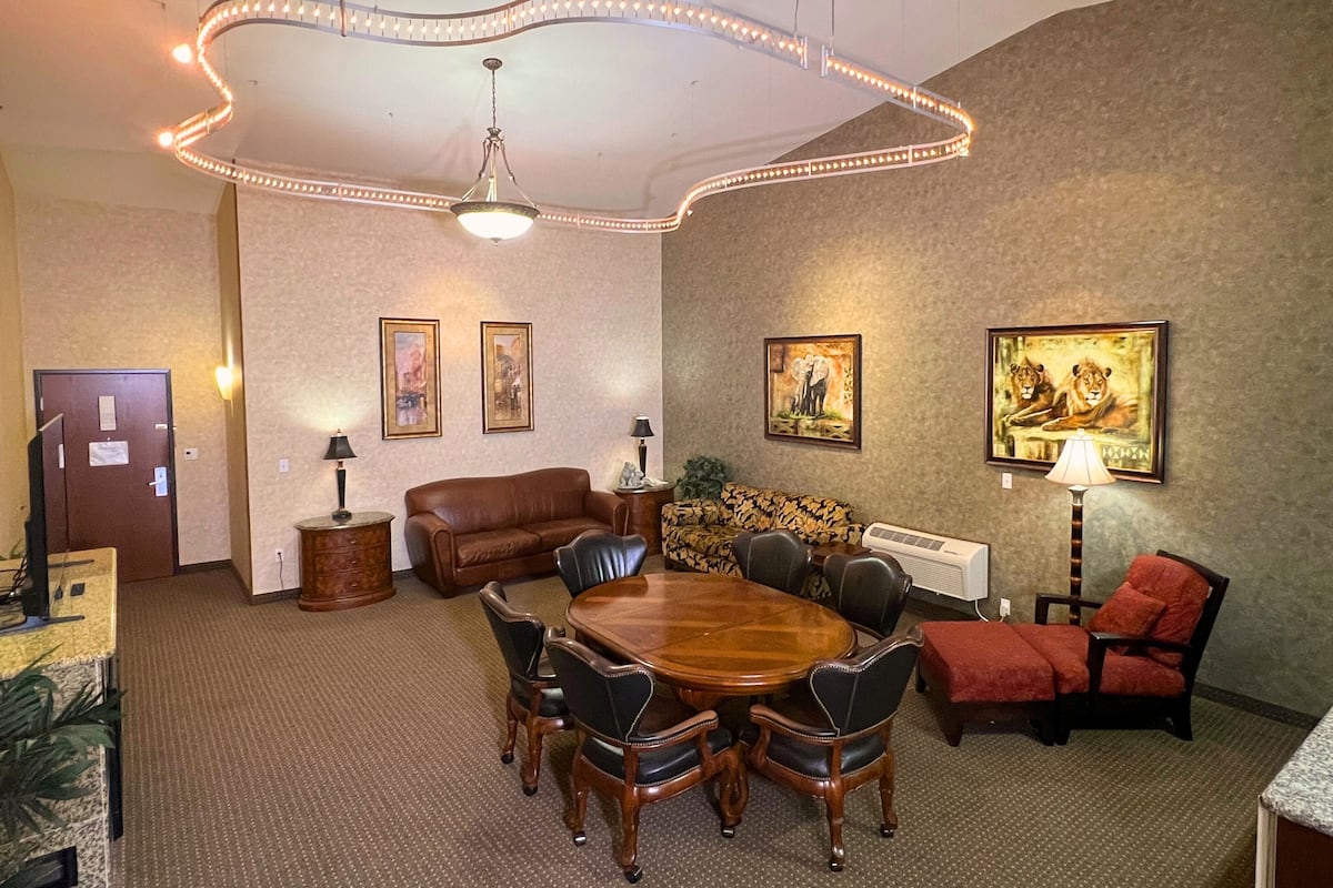 A conference room with a wooden table and leather chairs, a brown leather sofa, a red armchair, and two framed pictures on the wall.