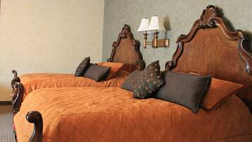 Uma cama de casal com cabeceira de madeira e duas luminárias de mesa.