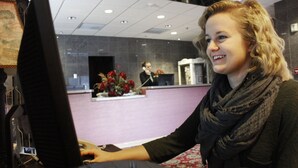 Una mujer en la recepción, con un monitor de computadora frente a ella.