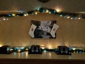 A wall with a framed picture, two Christmas stockings with letters, and three toasters on a counter.