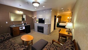 Habitación de hotel con sala de estar, kitchenette, chimenea y dormitorio separado.